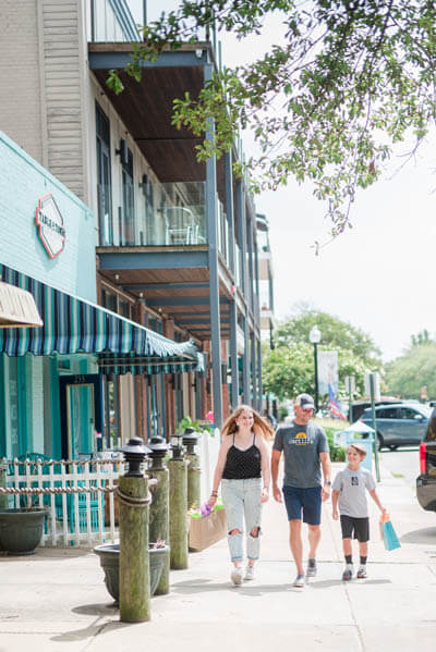 Family holding shopping bags and walking down a street