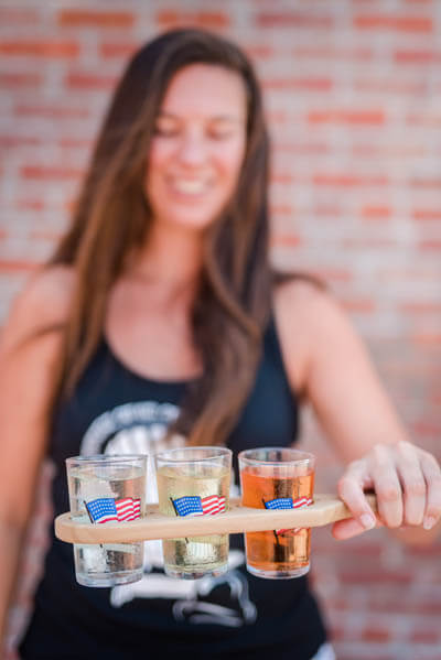 Woman holding three shot glasses at Cider Tasting